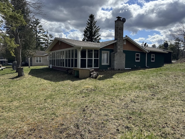 back of house with a lawn, a chimney, and a sunroom