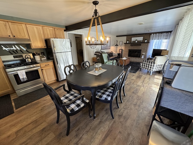 dining room with an inviting chandelier, dark wood-type flooring, and a brick fireplace