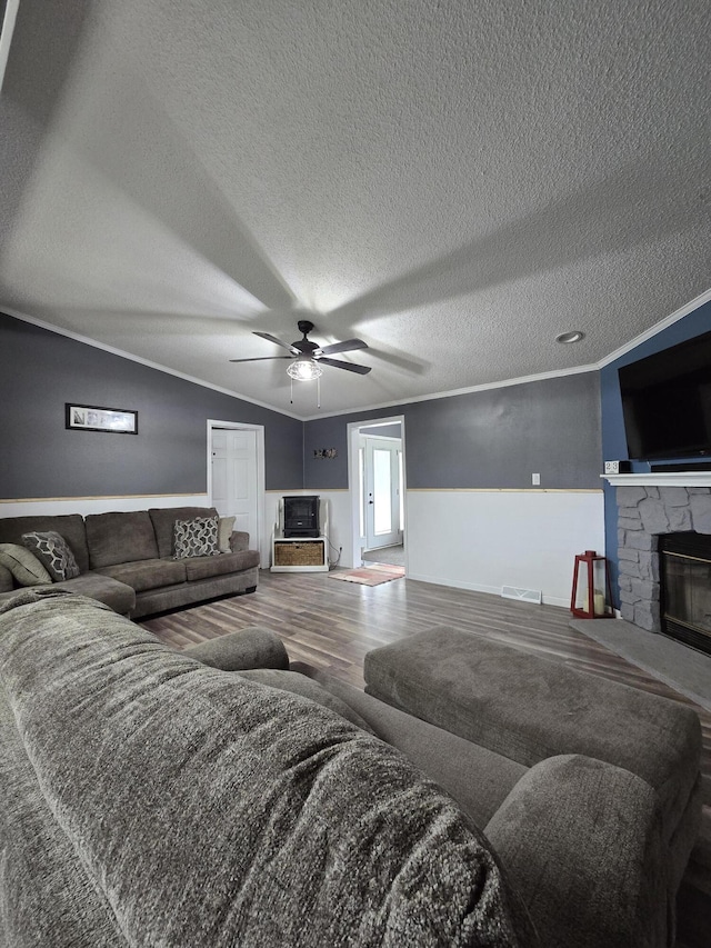 living area with a fireplace, a ceiling fan, visible vents, a textured ceiling, and wood finished floors