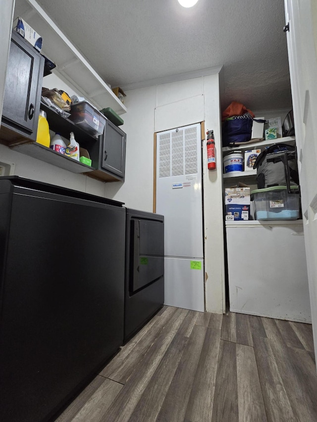 washroom with a heating unit, dark wood-type flooring, and a textured ceiling