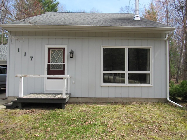 exterior space featuring a lawn and a shingled roof