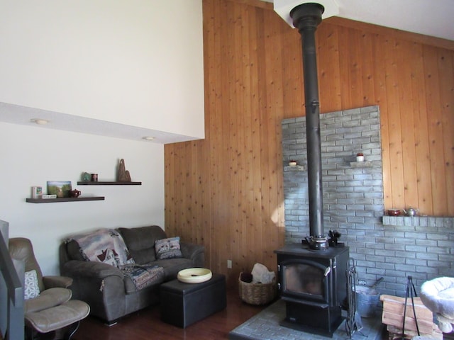 living area with a wood stove, wood walls, wood finished floors, and a towering ceiling