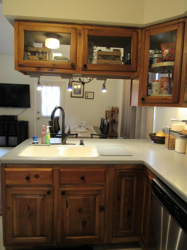 kitchen featuring light countertops, a sink, dishwasher, and glass insert cabinets