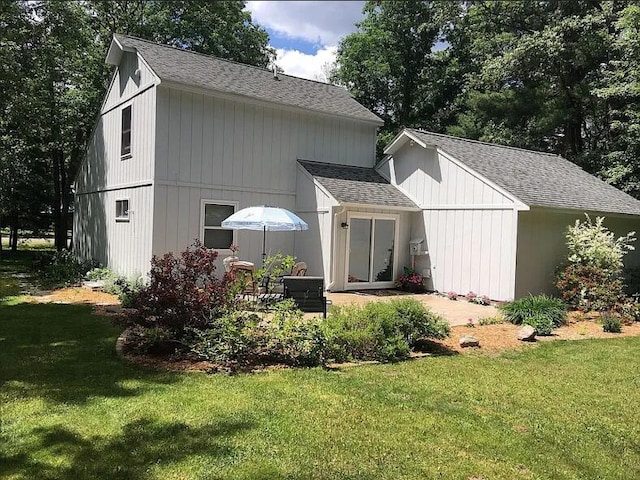 back of house featuring roof with shingles and a yard