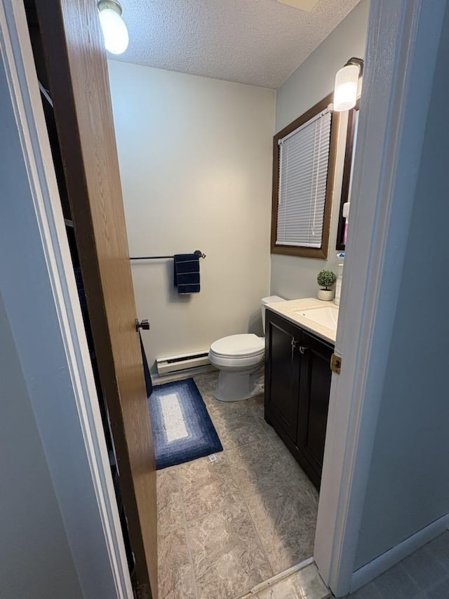 bathroom featuring vanity, baseboard heating, toilet, and a textured ceiling
