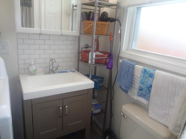 bathroom featuring backsplash, toilet, and vanity