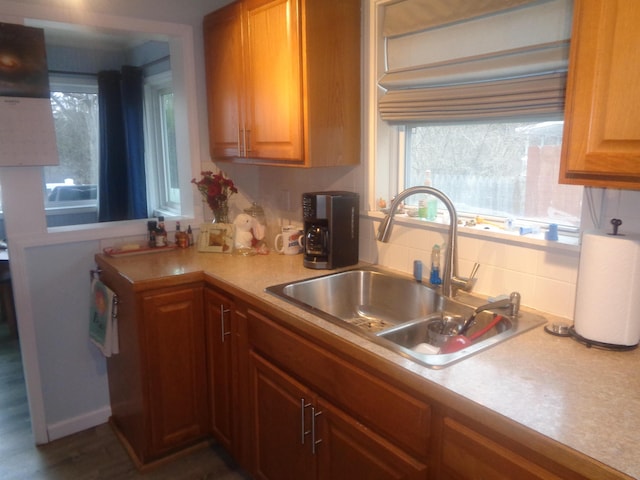 kitchen featuring backsplash, brown cabinets, light countertops, and a sink