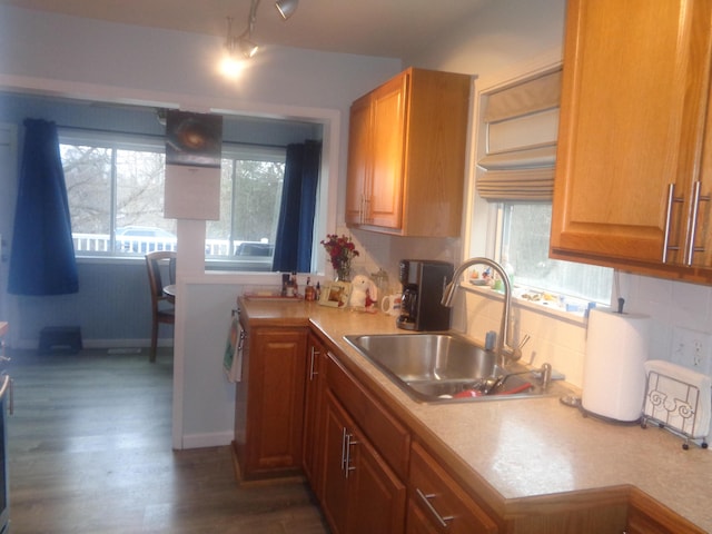 kitchen with dark wood-style flooring, a sink, light countertops, tasteful backsplash, and baseboards
