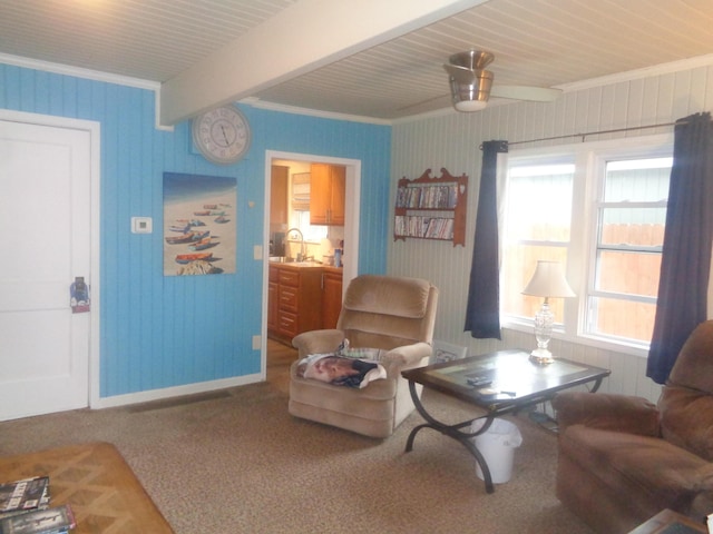 carpeted living room featuring ornamental molding, a sink, ceiling fan, and beam ceiling