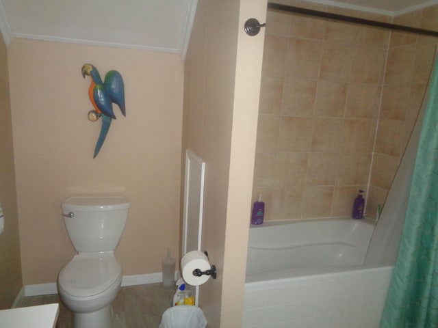 full bathroom with toilet, crown molding, tiled shower / bath combo, and baseboards