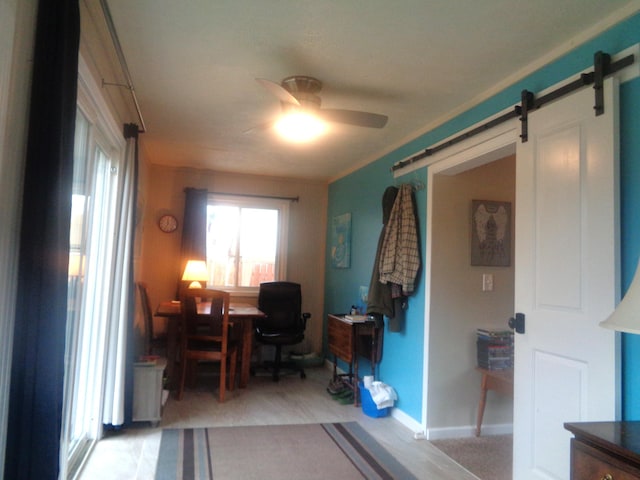 home office with a barn door, a ceiling fan, and baseboards