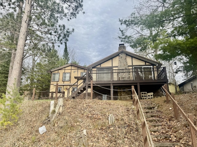 rear view of house with stairway, a deck, and a chimney