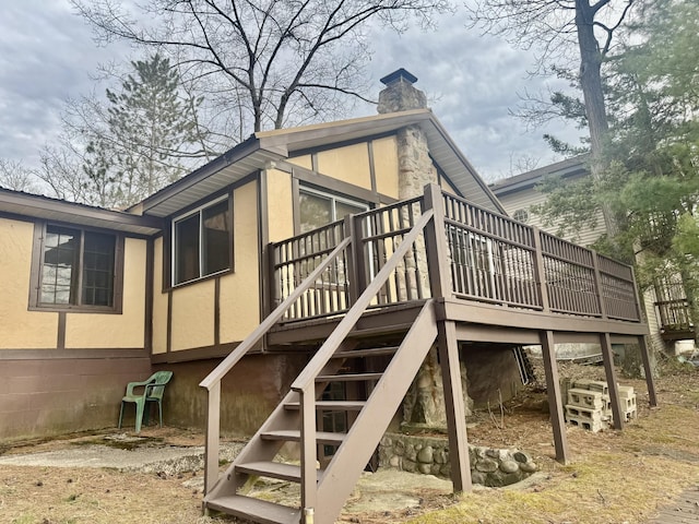 rear view of property with a deck, a chimney, and stairway