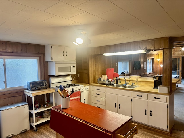 kitchen with a sink, wood walls, a toaster, and white appliances