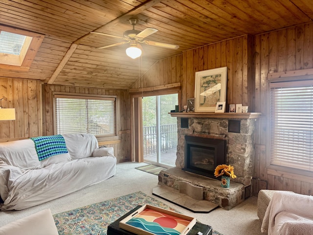 living area with carpet, wood walls, and a stone fireplace