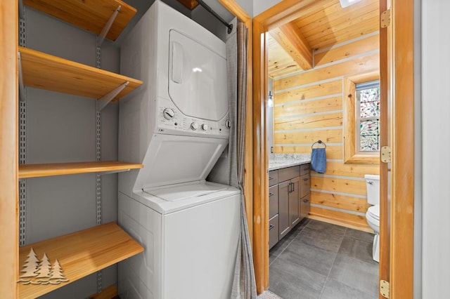laundry area with wooden walls, wooden ceiling, laundry area, and stacked washer / dryer