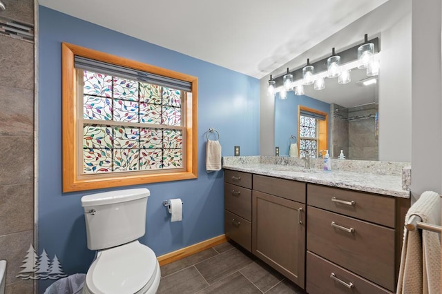 bathroom featuring baseboards, vanity, toilet, and tiled shower