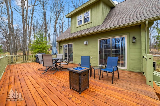deck featuring outdoor dining area and an outdoor fire pit