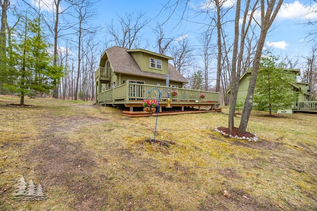 view of front of property featuring a shingled roof, a deck, and a front yard
