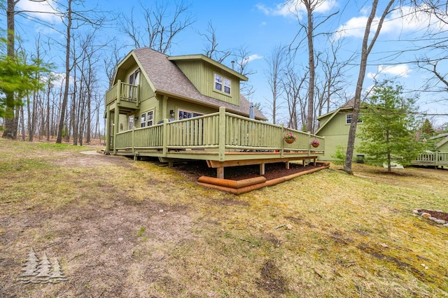 back of house with a shingled roof, a balcony, and a deck