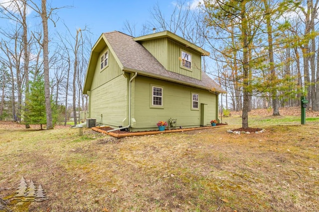 view of side of property with a shingled roof and central AC unit