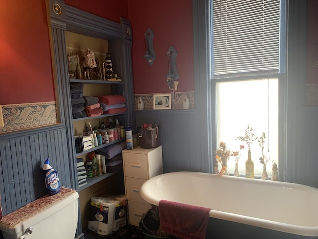 bathroom featuring wainscoting, a freestanding bath, and toilet