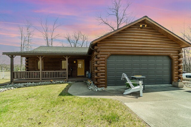log-style house with covered porch, a yard, log siding, a garage, and concrete driveway