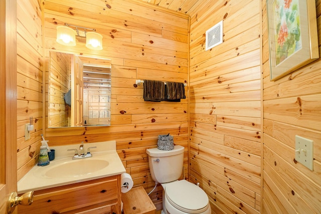 bathroom featuring wooden walls, toilet, visible vents, and vanity