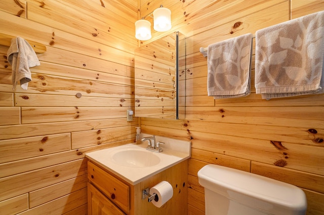 bathroom featuring wooden walls, vanity, and toilet