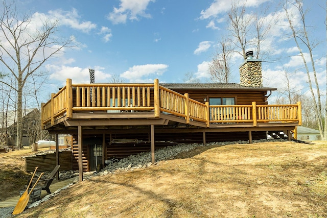 back of property with a chimney, log exterior, and a deck