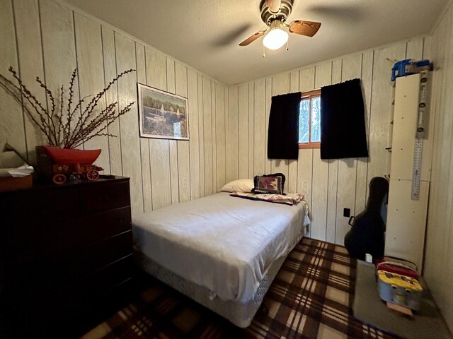 bedroom with wood walls and a ceiling fan
