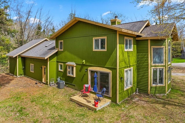 1406 Opal Lake Rd, Gaylord, MI 49735 - back of house with a chimney, a shingled roof, central AC unit, a deck, and a lawn