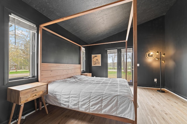 1406 Opal Lake Rd, Gaylord, MI 49735 - bedroom with wood finished floors, multiple windows, lofted ceiling, and access to exterior