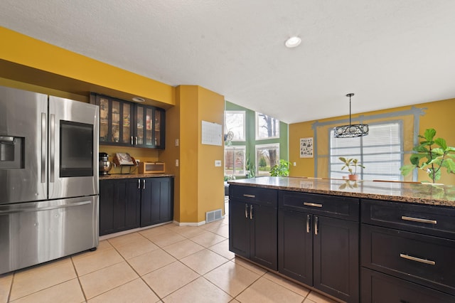 1406 Opal Lake Rd, Gaylord, MI 49735 - kitchen featuring stainless steel fridge, glass insert cabinets, light tile patterned flooring, dark stone counters, and pendant lighting
