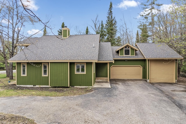 1406 Opal Lake Rd, Gaylord, MI 49735 - view of front of house with a shingled roof, a chimney, an attached garage, and asphalt driveway