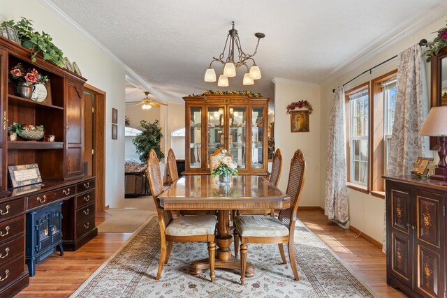 6075 W Edgar St, Pellston, MI 49769 - dining space with light wood finished floors, a chandelier, ornamental molding, baseboards, and ceiling fan