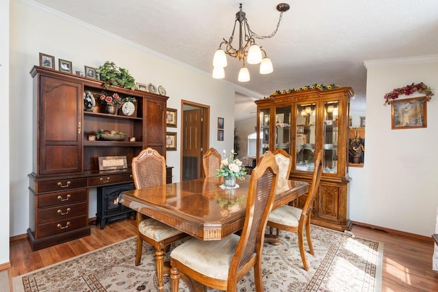 6075 W Edgar St, Pellston, MI 49769 - dining area featuring a chandelier, light wood finished floors, crown molding, and baseboards