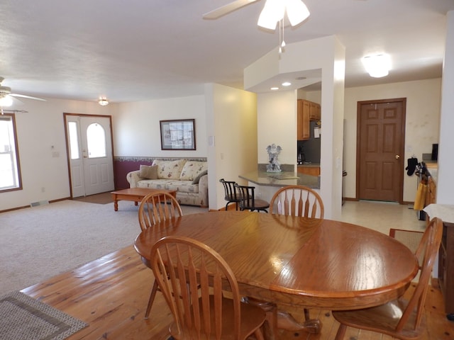 dining room with a ceiling fan, light wood-style floors, visible vents, and baseboards
