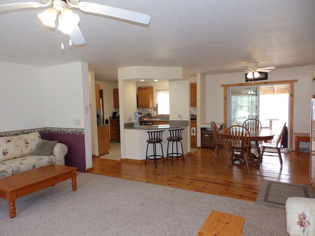 living area featuring light wood-type flooring and a ceiling fan