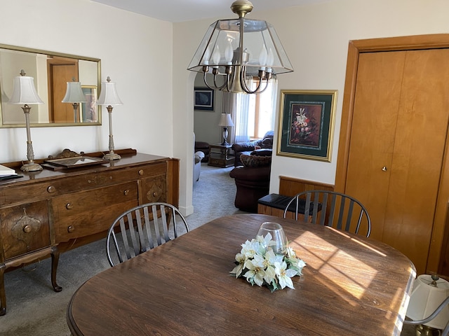 carpeted dining room with an inviting chandelier