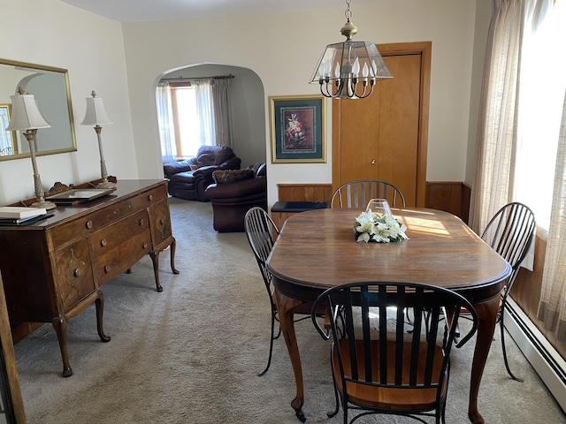 dining area featuring arched walkways, a notable chandelier, light carpet, and a baseboard radiator