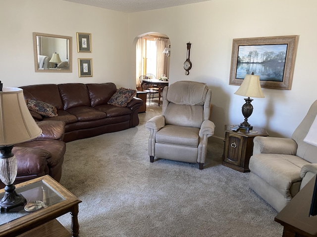 living area with carpet floors and arched walkways