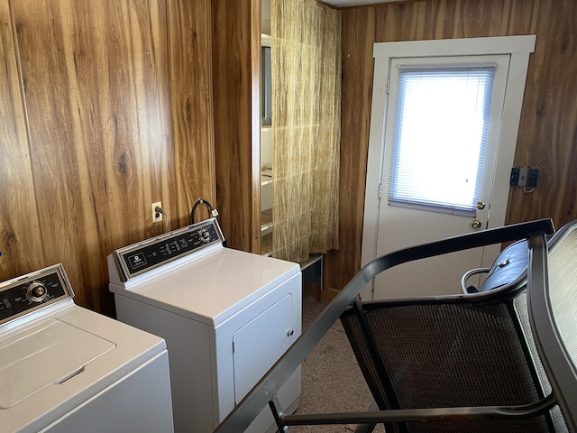 clothes washing area featuring carpet, laundry area, wood walls, and washing machine and clothes dryer