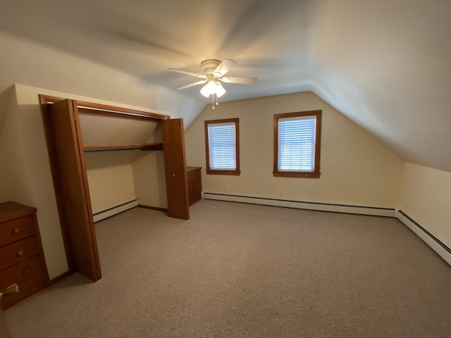 unfurnished bedroom featuring ceiling fan, lofted ceiling, baseboard heating, and light carpet