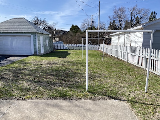 view of yard featuring a detached garage, fence, and an outdoor structure