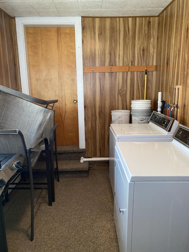 laundry room with wooden walls, carpet floors, and washing machine and clothes dryer