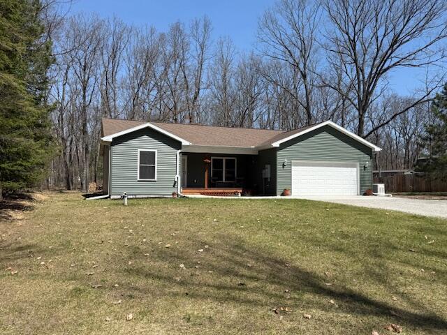 ranch-style house featuring covered porch, a front yard, cooling unit, an attached garage, and driveway