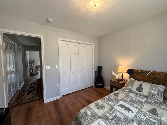 bedroom with baseboards, wood finished floors, and a closet