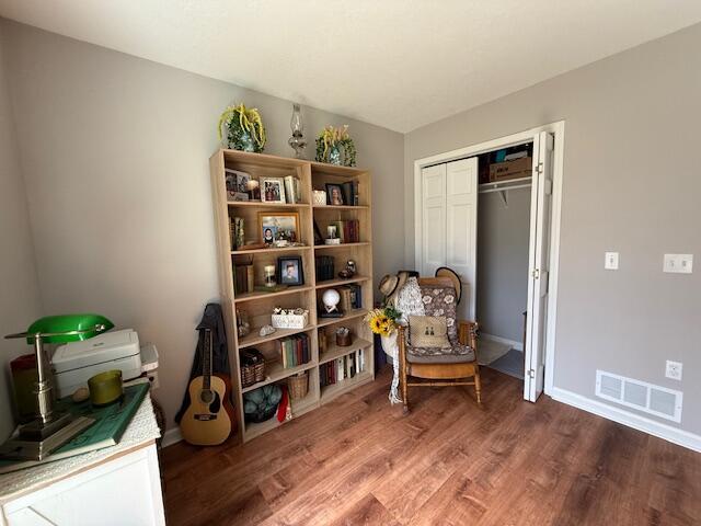 living area with visible vents, baseboards, and wood finished floors