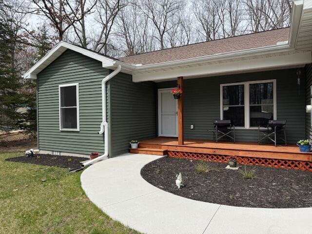 single story home with a shingled roof, covered porch, and a front yard